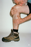Holding knee in pain with hiking boot