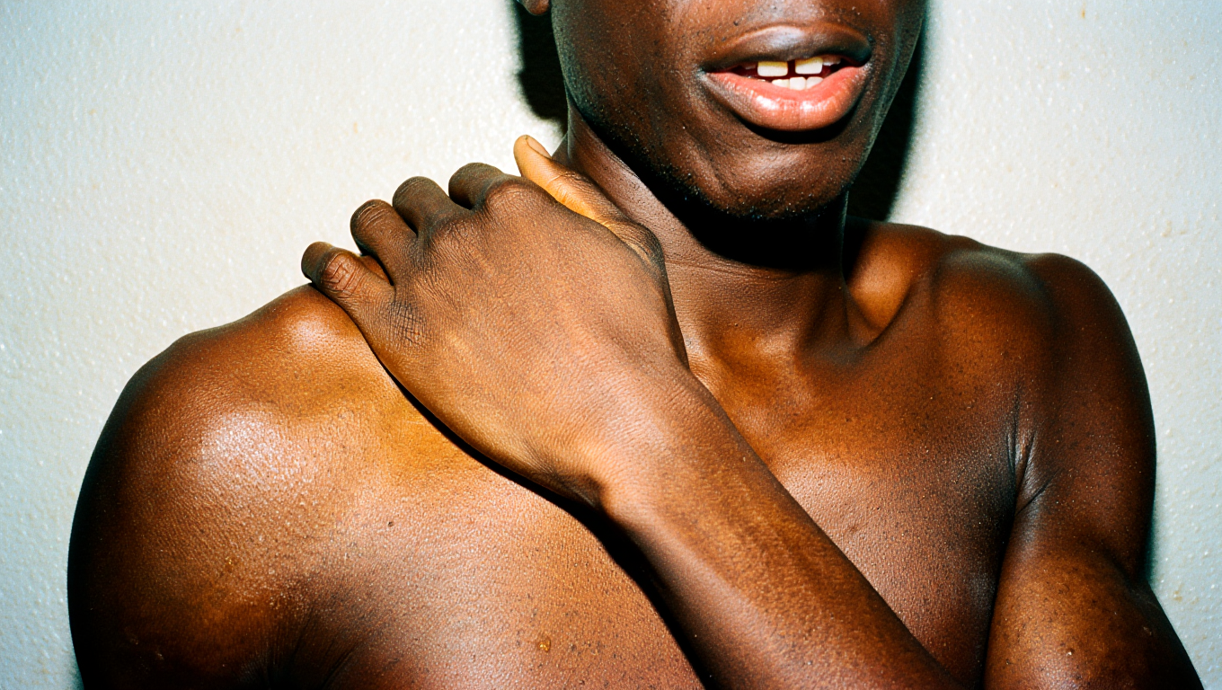 Person rubbing  their shoulder against a plain background