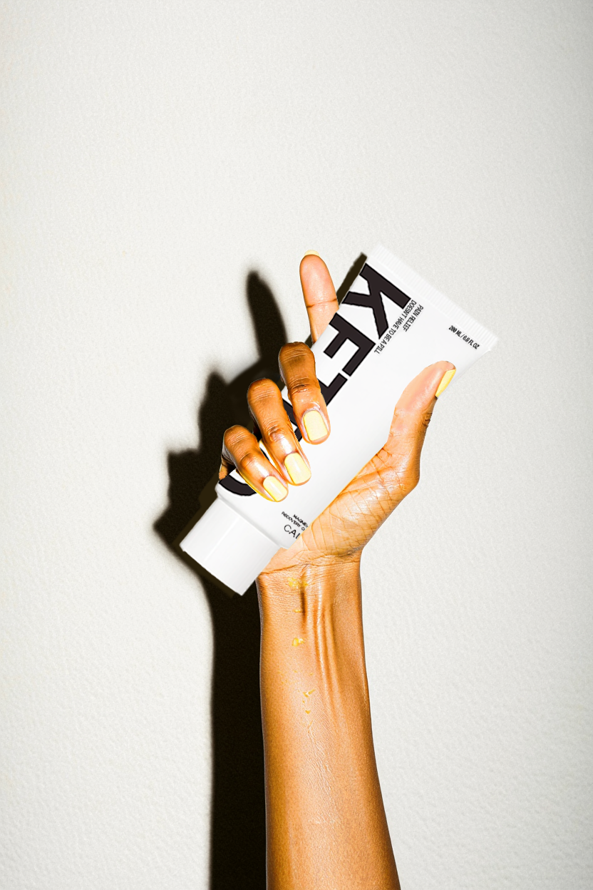 Hand with short, yellow painted finger nails, holding a white tube with Ketro logo